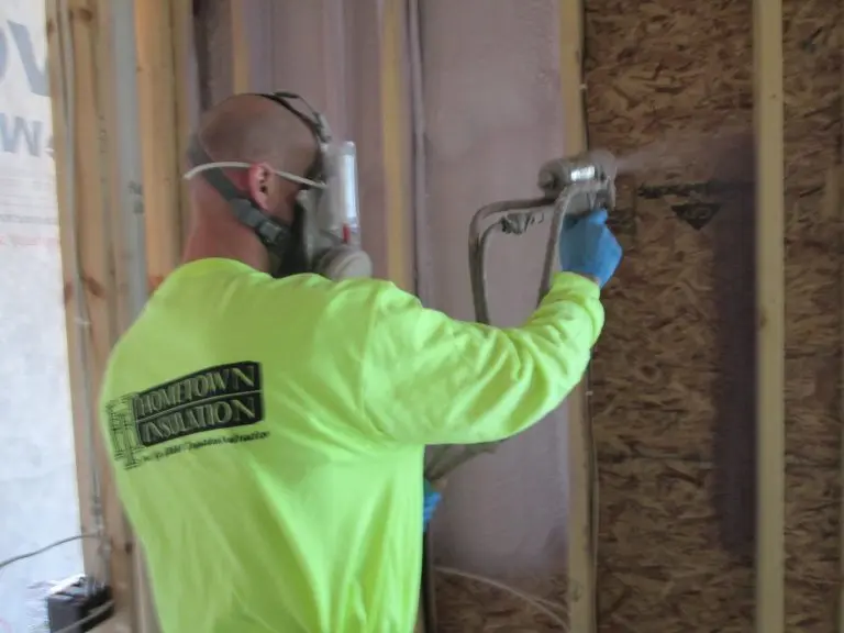 Hometown Insulation team member installing new insulation in a house