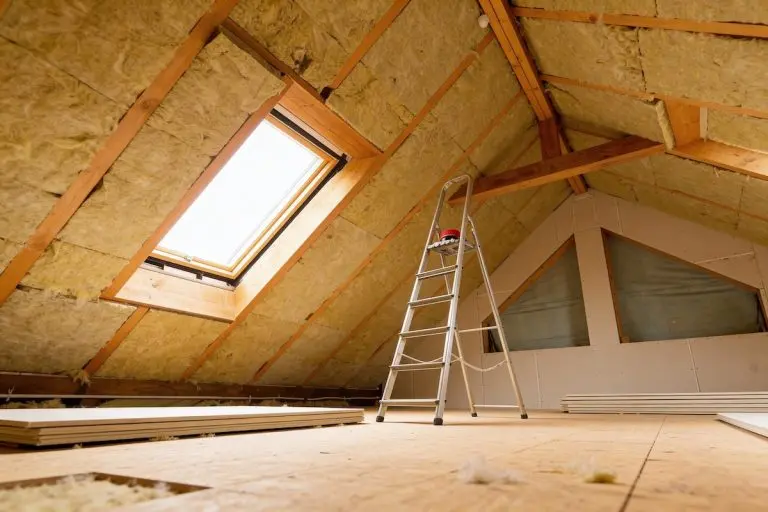 Under construction attic space featuring exposed wooden beams, mineral wool insulation, a skylight, and a ladder ready for work