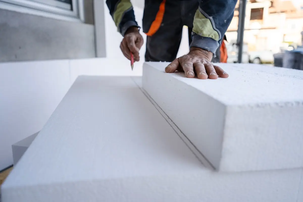 Worker use pen to mark the correct length and dimension of styrofoam during the wall insulation process at the construction site to cut the right size of the board