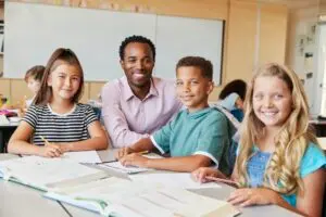male school teacher and kids in class smiling to camera