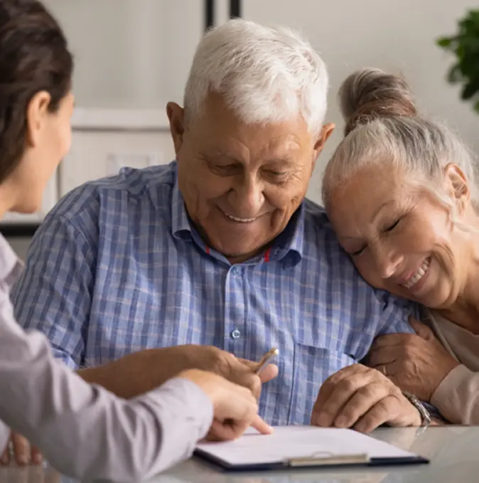 a senior couple happily signing a contract at a table, indicating a significant agreement or decision