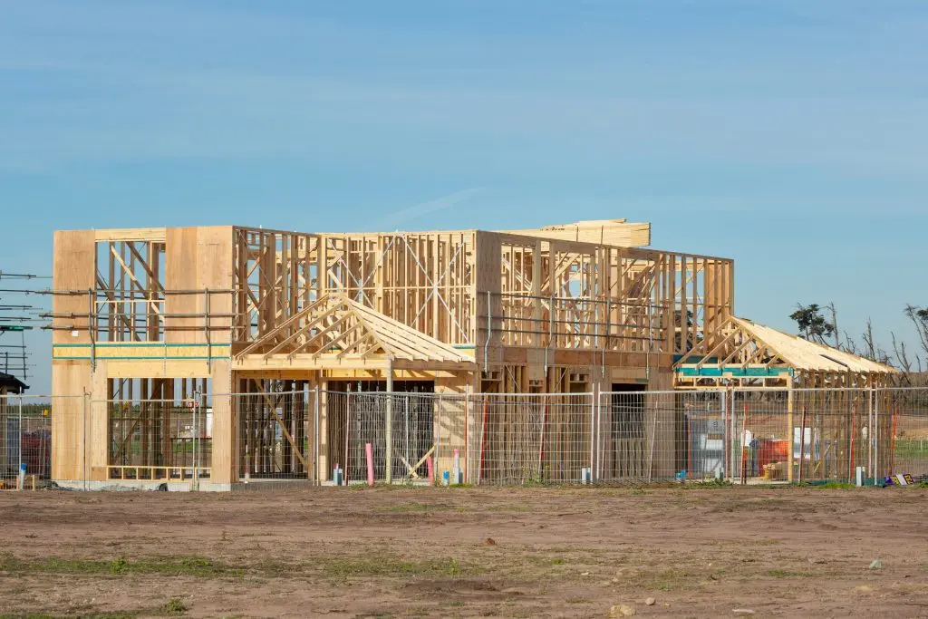 Stages of building a custom home showing a residential house under construction with wood framing.