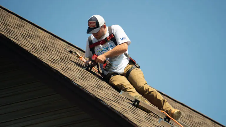 worker on top of shingles fixing roof