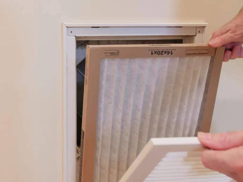 HVAC-service-technician-replacing-dirty-indoor-air-filter-in-residential-heating-and-air-conditioning-system