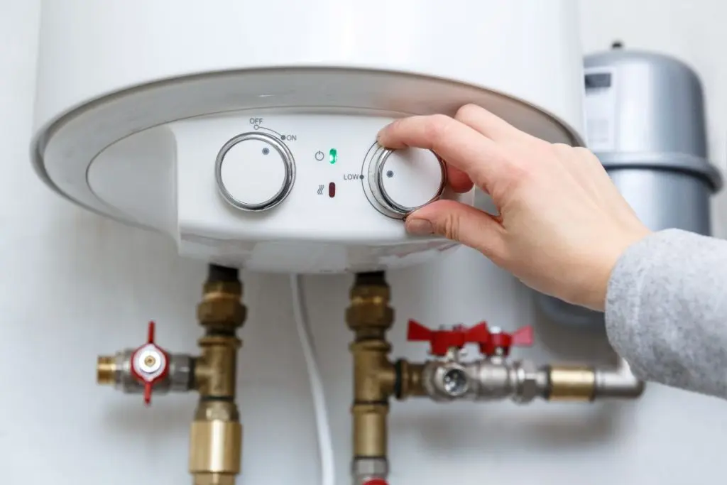 Female-hand-puts-thermostat-of-electric-water-heater-boiler-in-low-low-power-consumption-mode