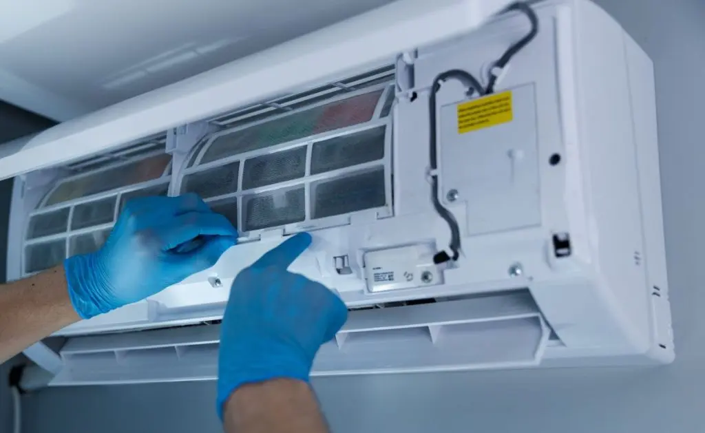 Professional Technician Performing Maintenance on a Split Air Conditioning Unit with Focus on Filter Replacement