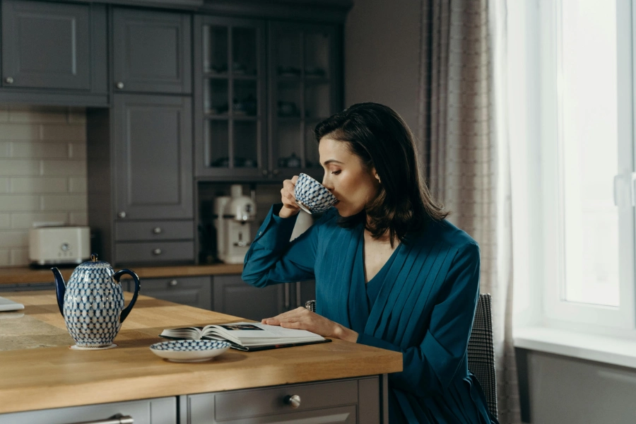 A woman sitting at a kitchen island drinking coffee.