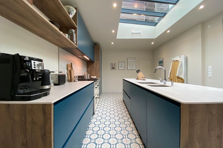 modern kitchen with blue cabinets, skylight, and patterned tile flooring