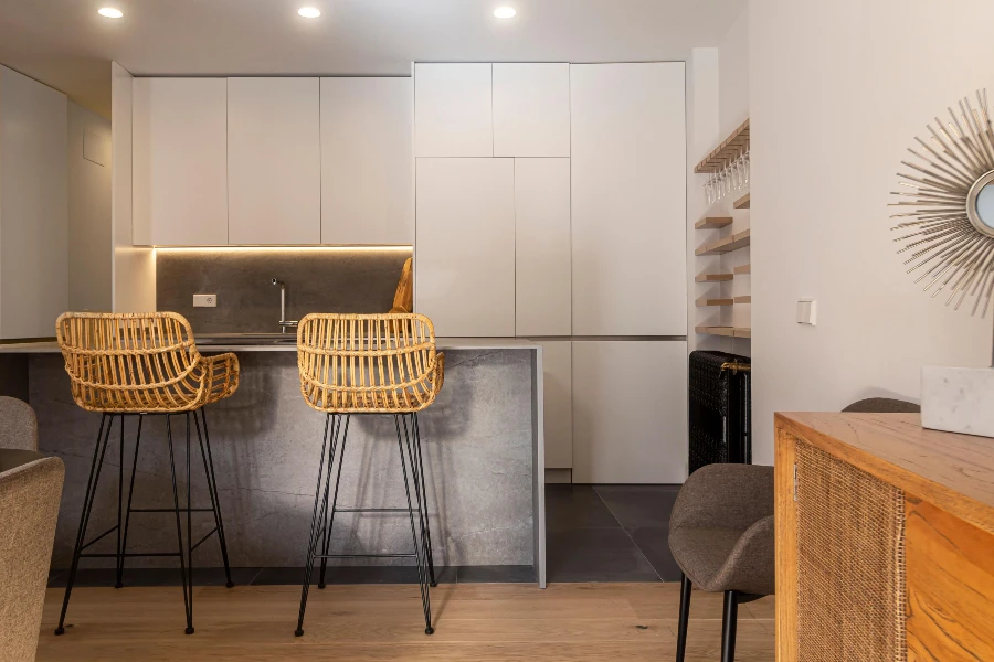 modern kitchen with two rattan bar stools at a gray breakfast counter