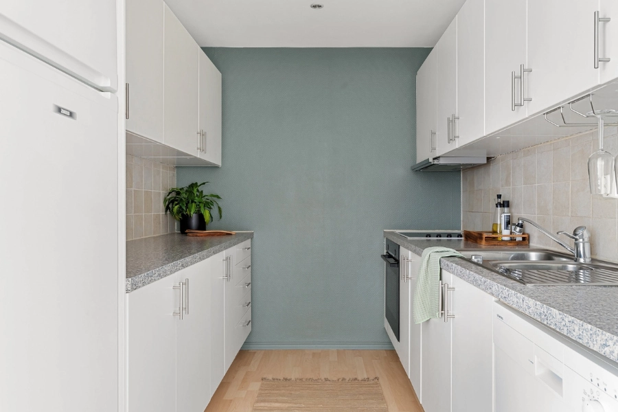 A sink positioned close to the stove and fridge.