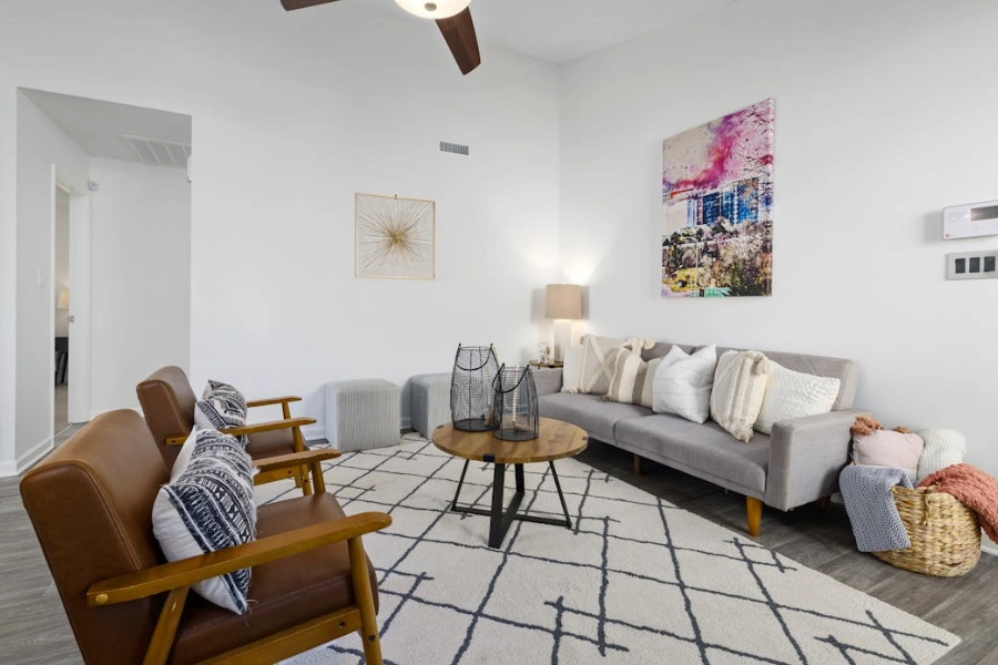 Elegant and minimalistic living room with gray sofa, wooden armchairs, and stylish decor.