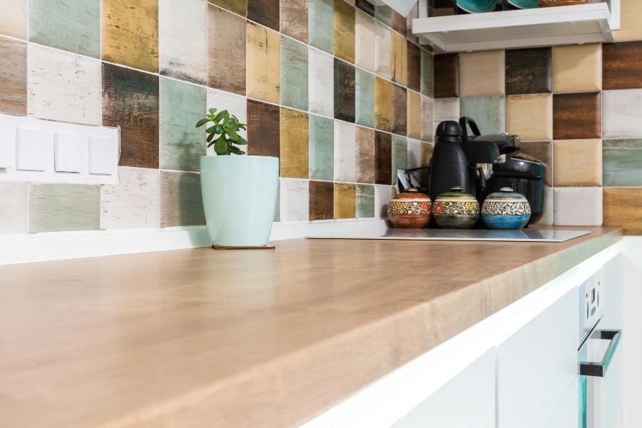 wooden kitchen countertop with a colorful tile backsplash and everyday kitchenware.
