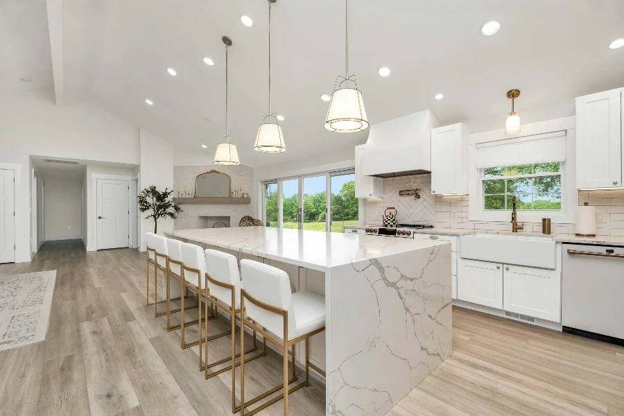 brightly lit kitchen area with large marble island