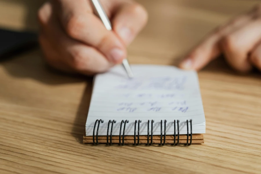 person writing in notebook with a pen