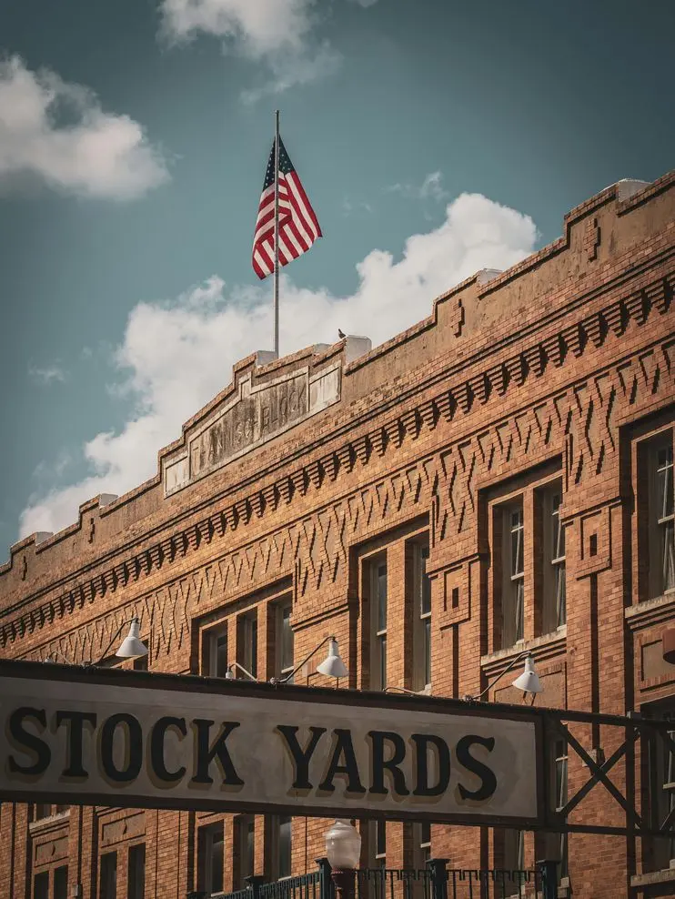 Brick facade of Fort Worth Stockyards building with American flag under a clear sky.