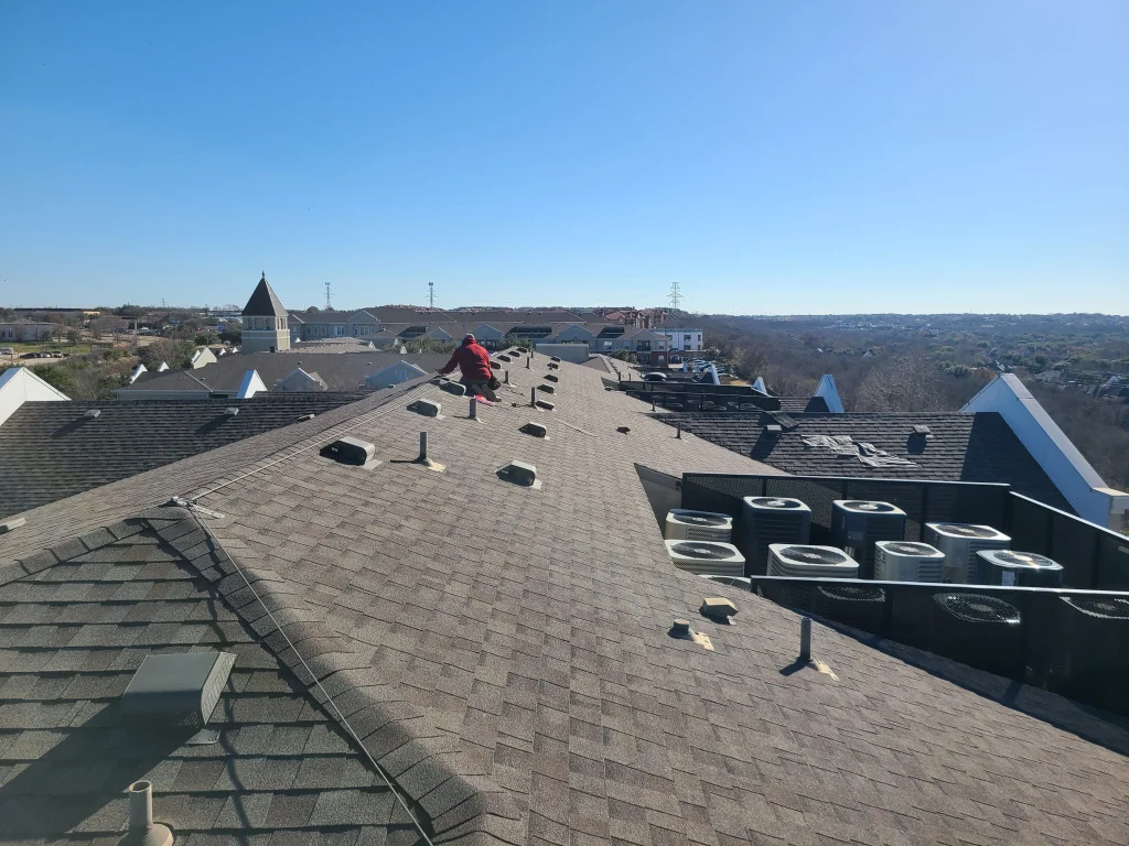 Roofer installing roof vents during an apartment shingle re-roof