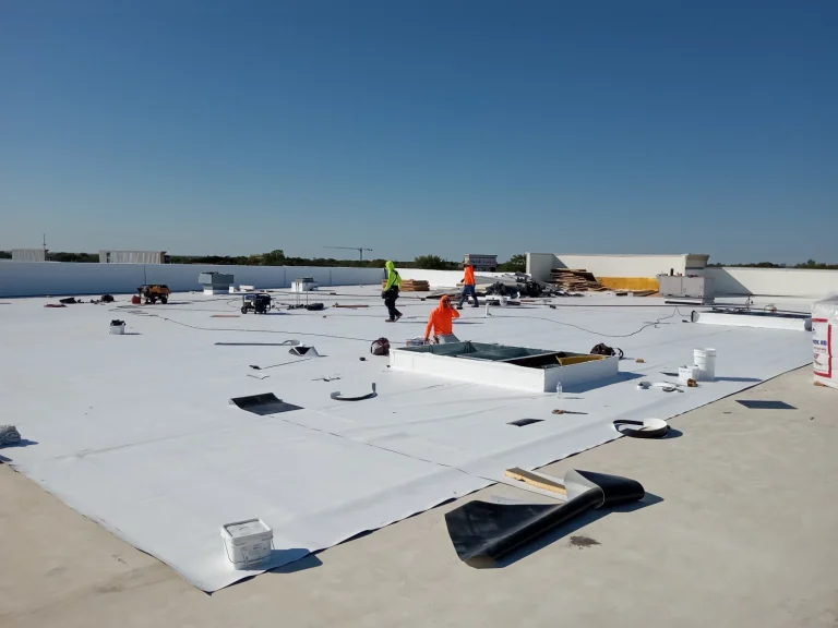Crew rolling out and welding TPO membrane on a commercial flat roof