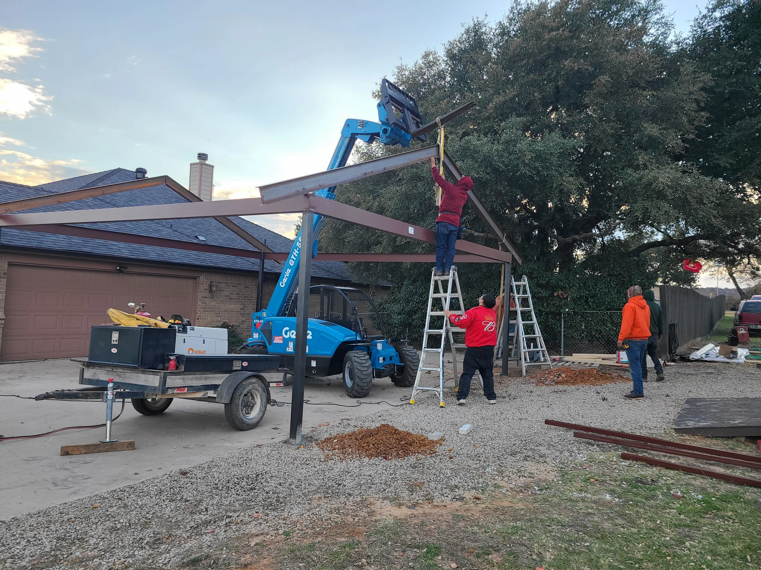 Crew setting a metal canopy roof section with a crane