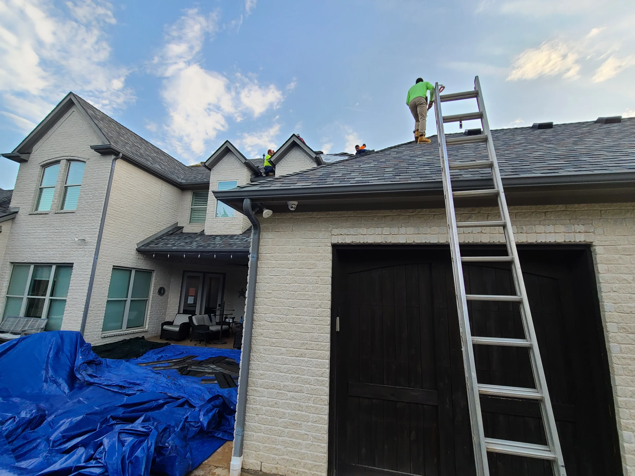 Roofer making a shingle roof repair on a two-story home
