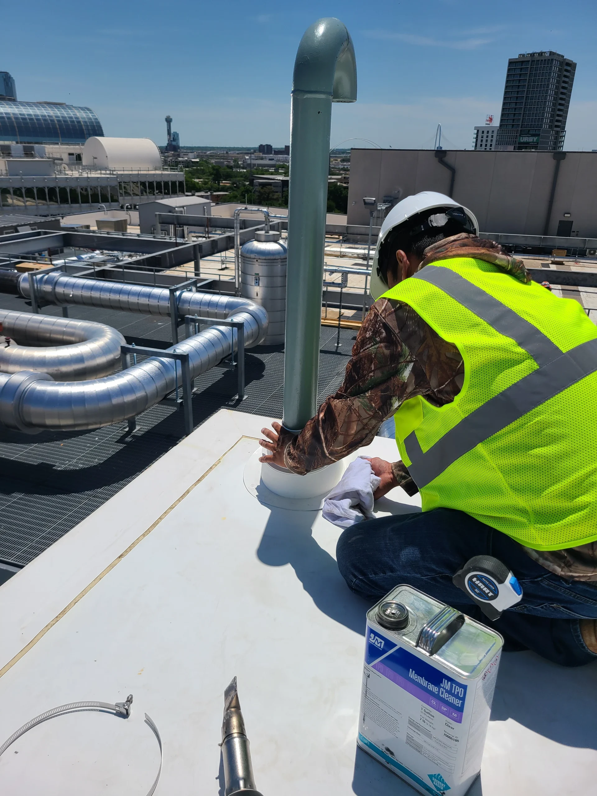 Roofer sealing pipe penetrations on a commercial flat roof