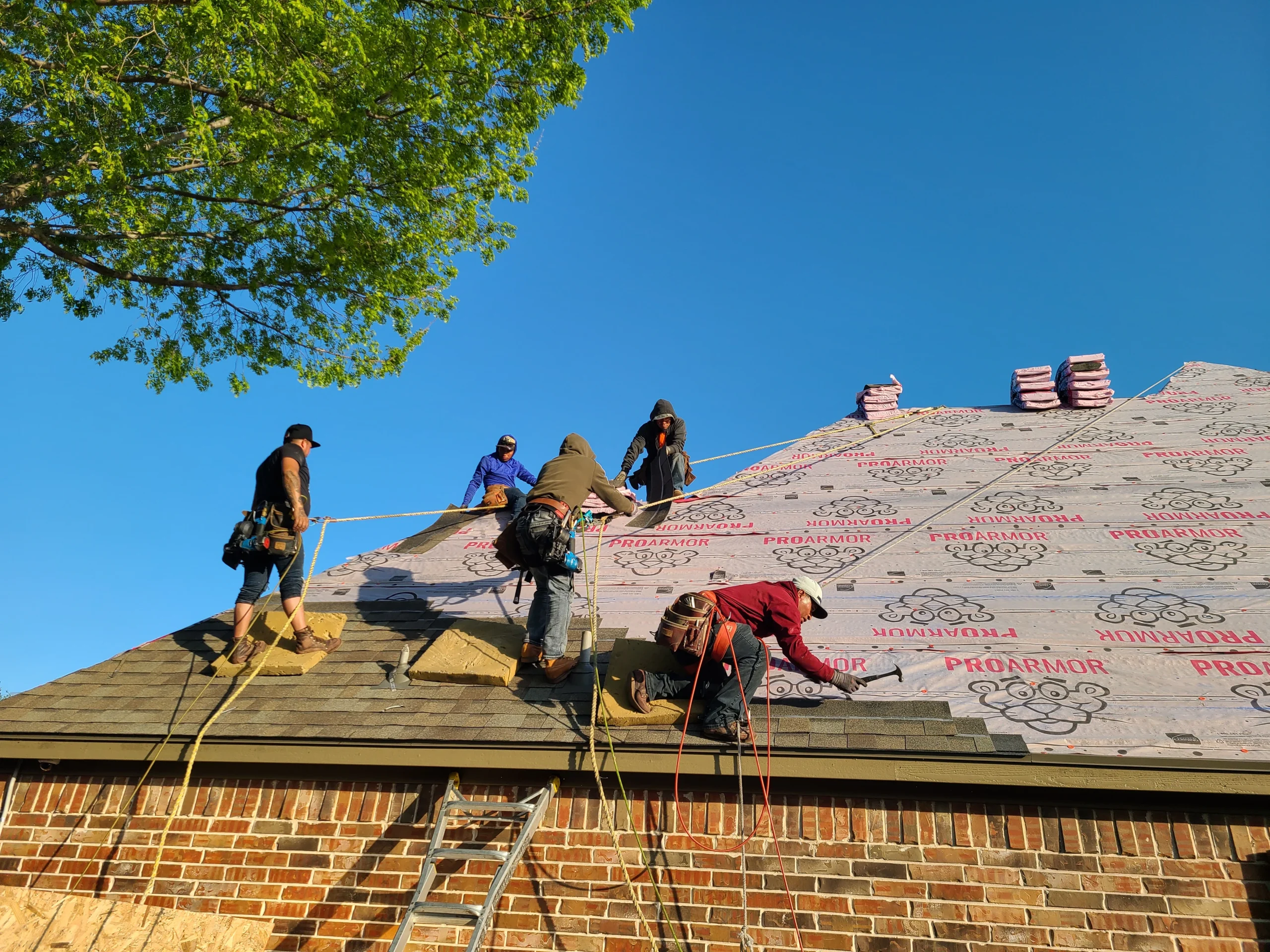 Roofing crew installing a steep-slope roof with fall-protection safety gear