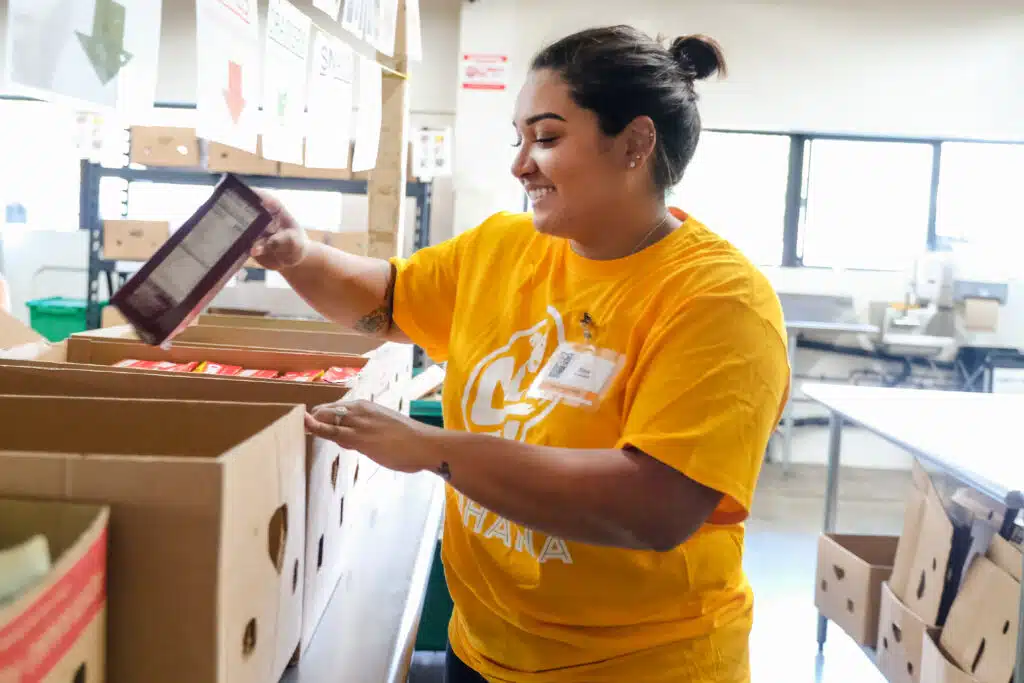 Volunteer Rina sorts boxed foods by category.