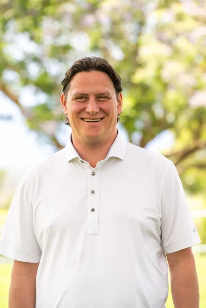 Smiling man in white shirt outdoors.