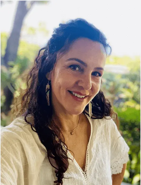 Smiling woman outdoors in white blouse.
