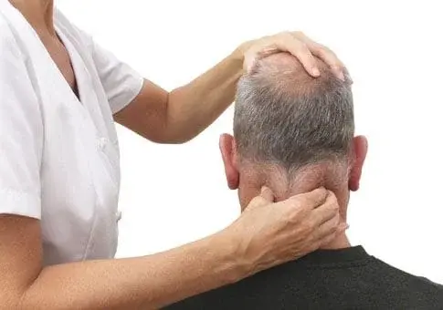 Massage therapist treating man's neck pain.