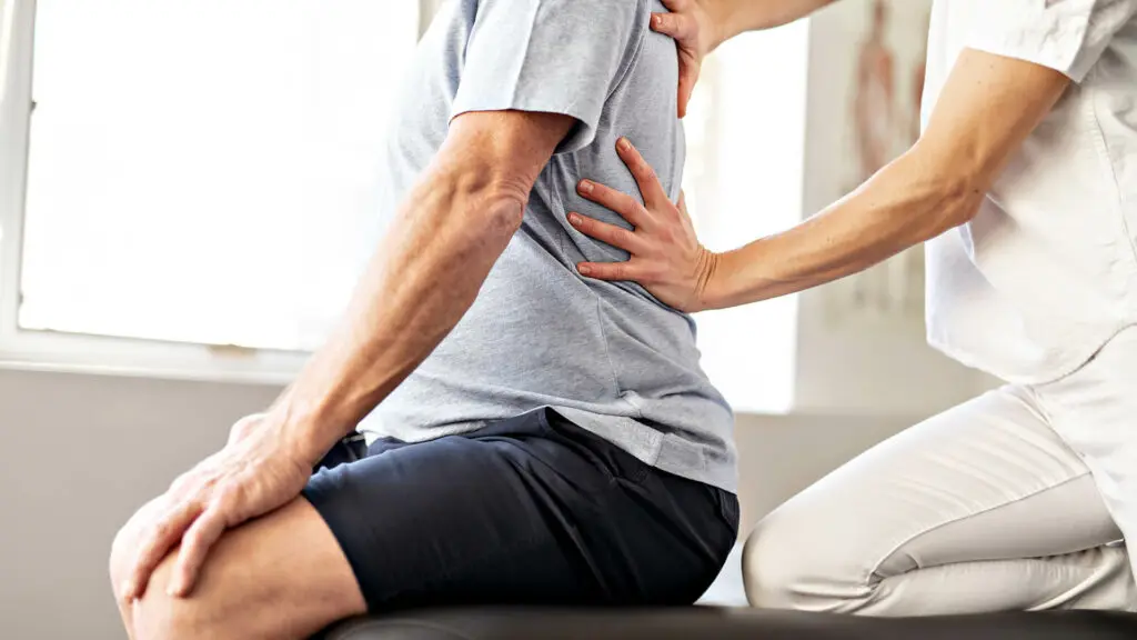 Physiotherapist treating patient's back pain.