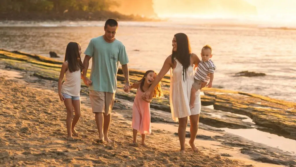 Family walking on a beach at sunset.