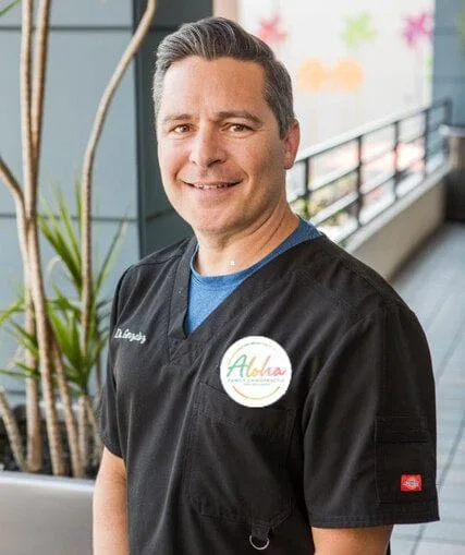 Smiling man in black scrubs, indoor setting.