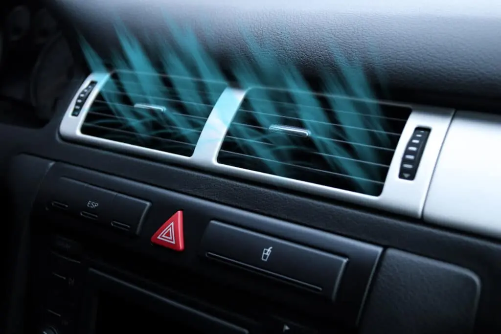 Car air conditioning vents with blue airflow lines indicating cool air being emitted.