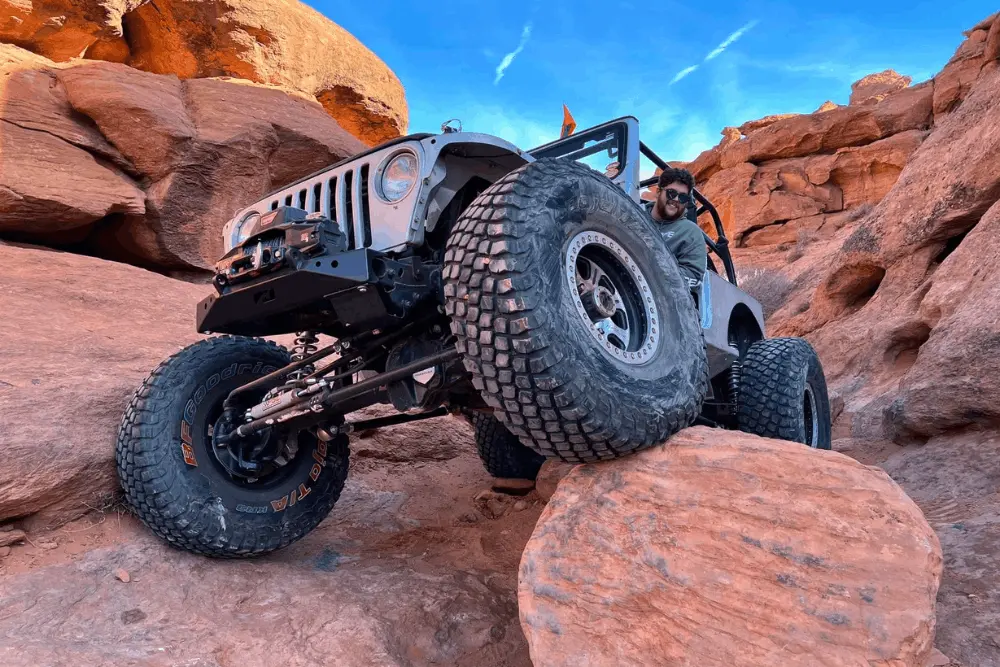Tire size and gear ratio, off-road and repair by Barney Brothers Off Road & Repair in Grand Junction, CO. Image of a lifted Jeep rock crawling over large boulders with oversized off-road tires and upgraded axle components. Highlighting traction, drivetrain performance, and extreme terrain safety.