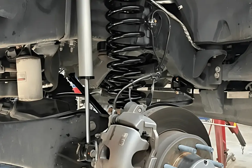 off-road suspension, Off-Road and Repair in Grand Junction, CO at Barney Brothers Off-Road and Repair. Close-up of a vehicle's suspension system, showing a new shock absorber, coil spring, and brake assembly.