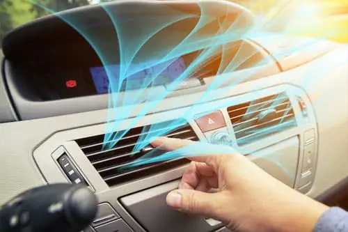 Hand adjusting car A/C vent with blue airflow lines indicating cool air distribution.