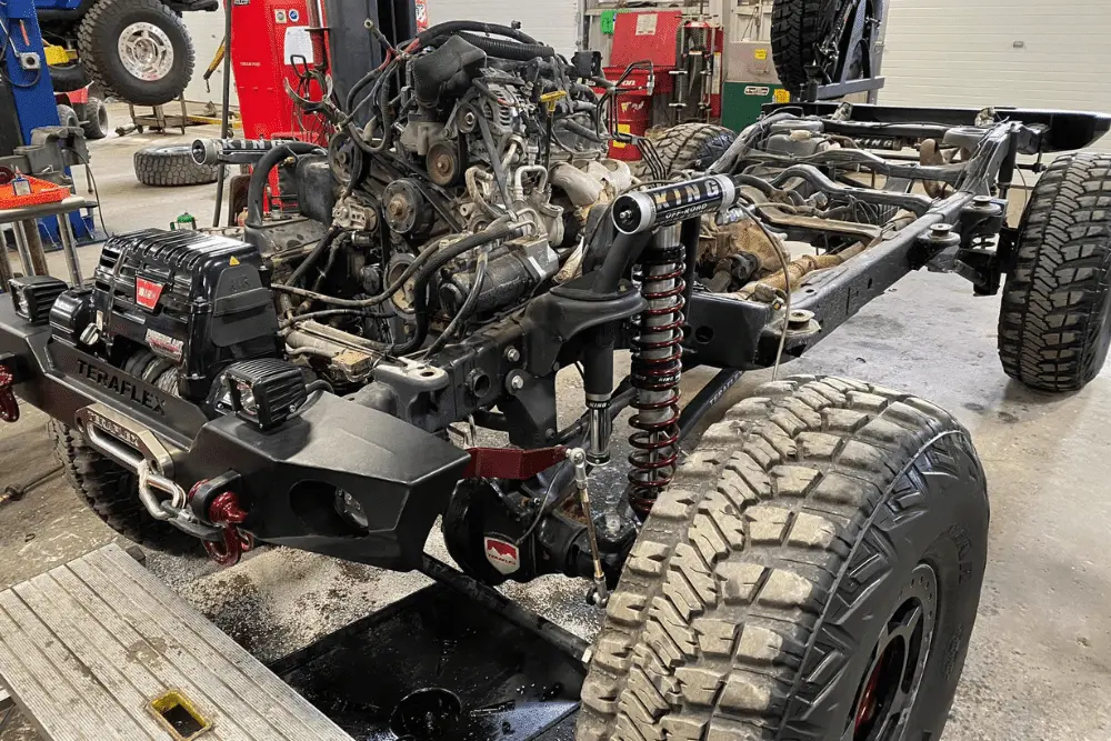Engine replacement, auto repair in Grand Junction, CO by Barney Brothers Off-Road and Repair. Image of a lifted Jeep chassis undergoing suspension and engine work, showcasing custom shocks, rugged tires, and performance upgrades for off-road enthusiasts.