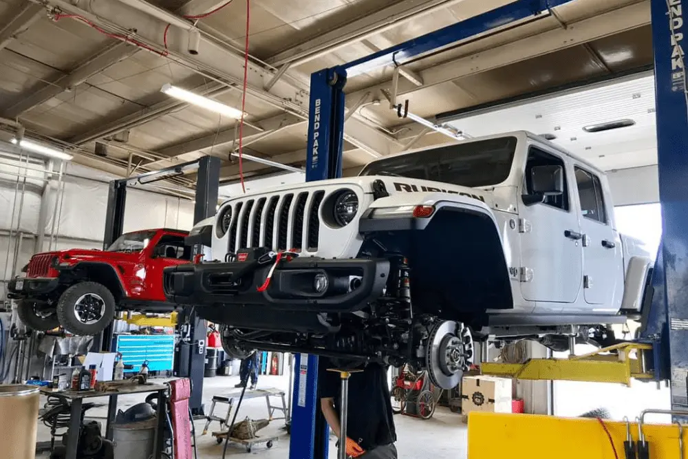 jeep repairs and upgrades, Off-Road and Repair in Grand Junction, CO at Barney Brothers Off-Road and Repair. White and red Jeep Rubicons on lifts in an auto repair shop undergoing repairs.