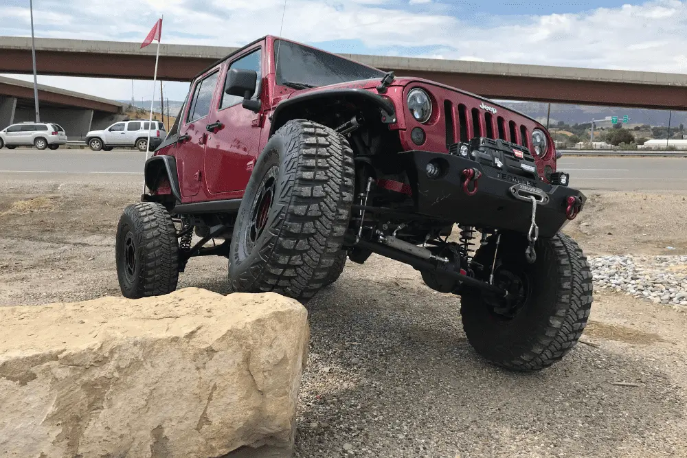 Lift Kit installation in Grand Junction, CO by Barney Brothers Off Road & Repair. Image of a lifted Jeep Wrangler flexing on a large rock, showcasing the shop’s commitment to performance, durability, and trail-ready capability.