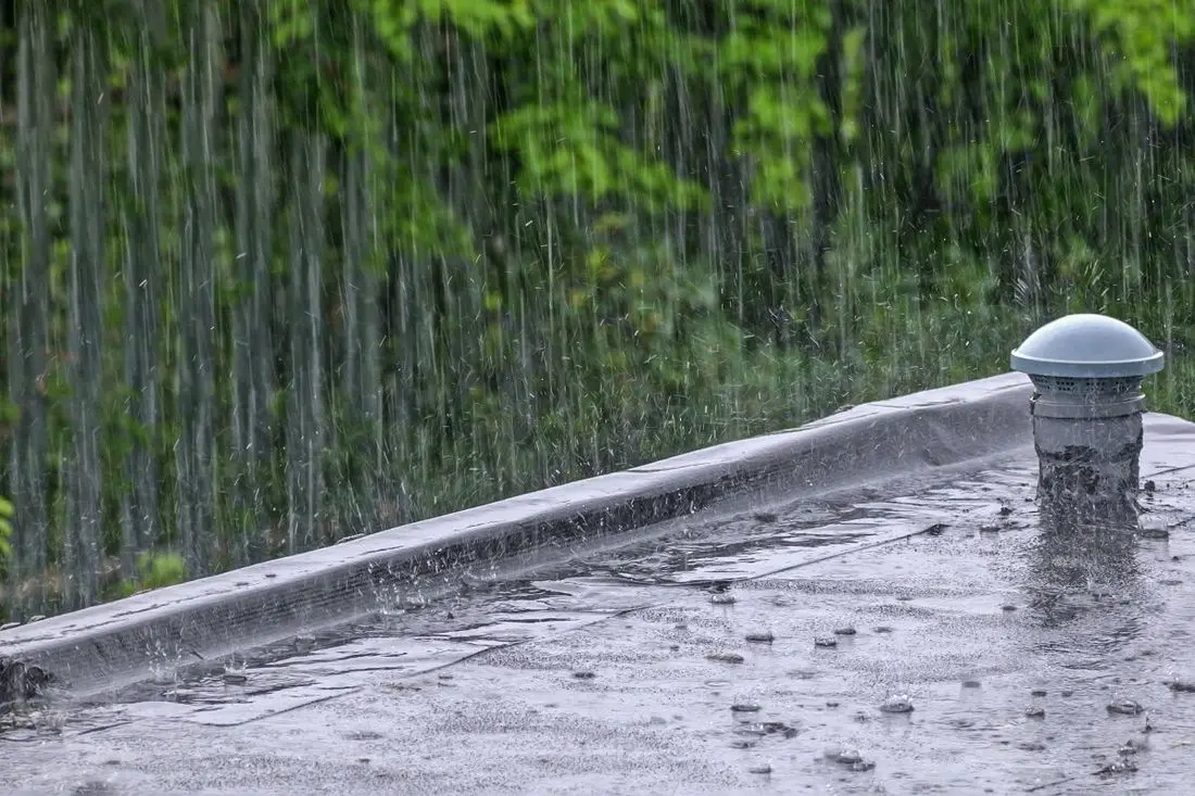 Rainwater streams pour on the roof of the building