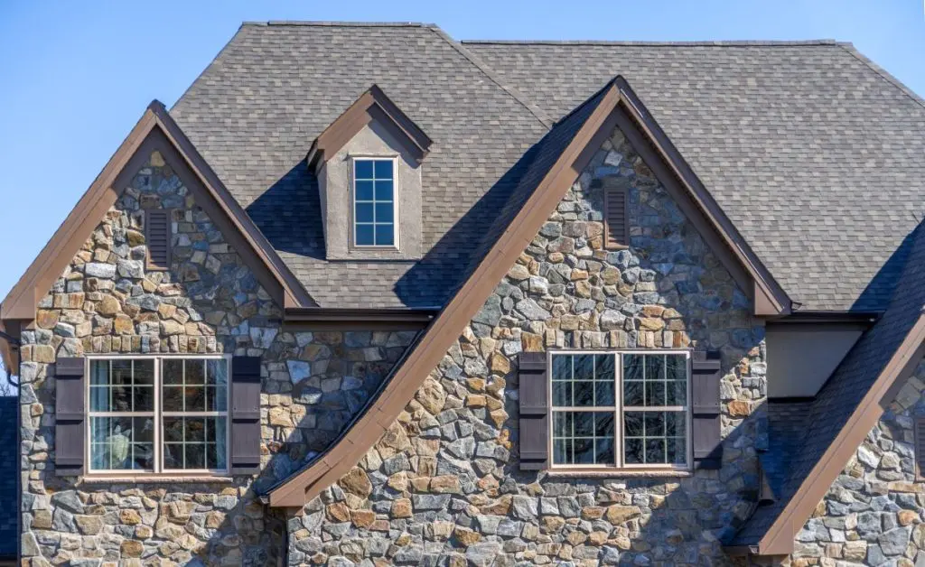Double gable with dark stone veneer siding, with triangle shape peaks, on a pitched roof attic