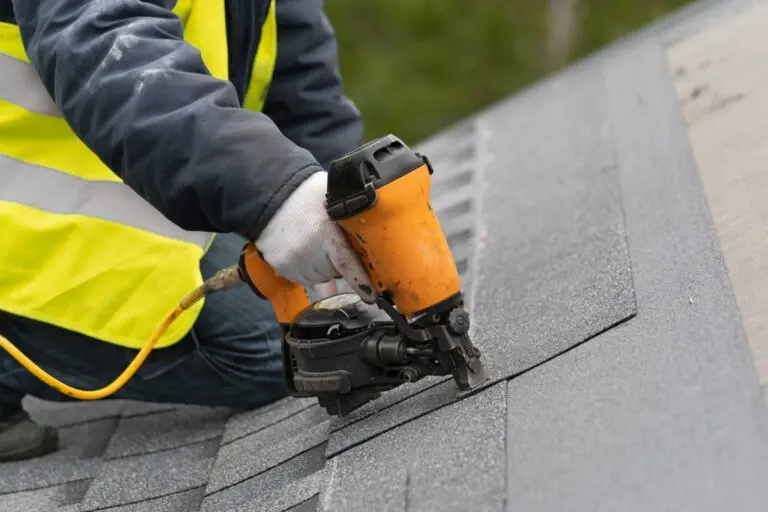 roofer using nail gun to install shingles