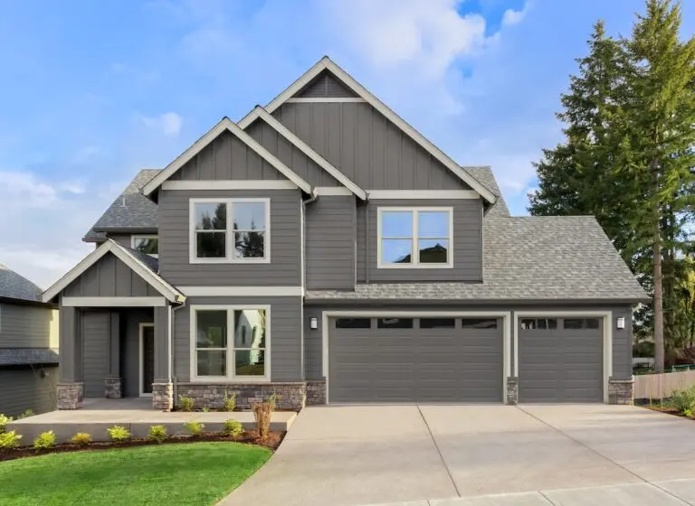 Roofing Stillwater Front exterior of new home on sunny day. Features covered porch, three car garage, and gables