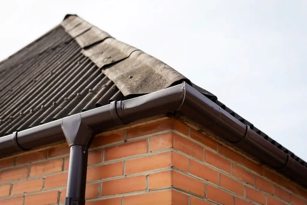 Detailed view of brick roof intersection. Focus on gutter connection at brick building corner