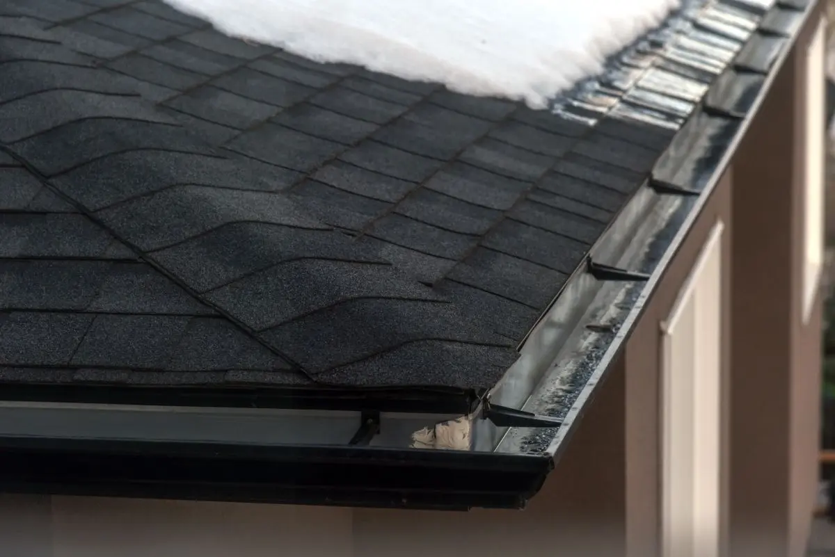 Snow melting on a black shingle roof