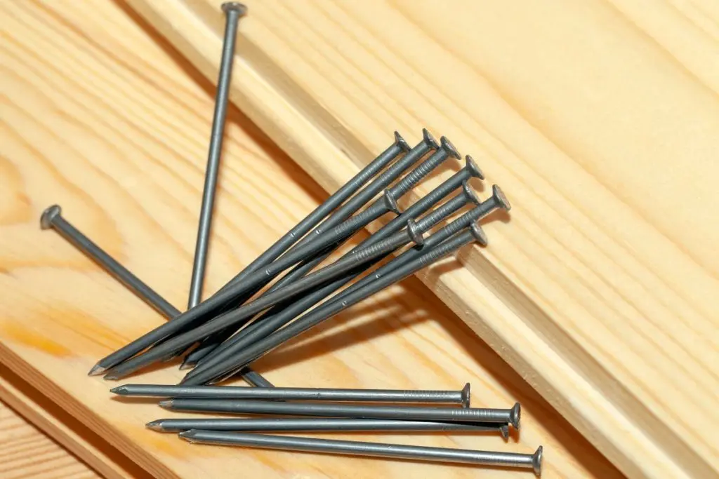 yellow-orange pine wood board and steel nails during construction work