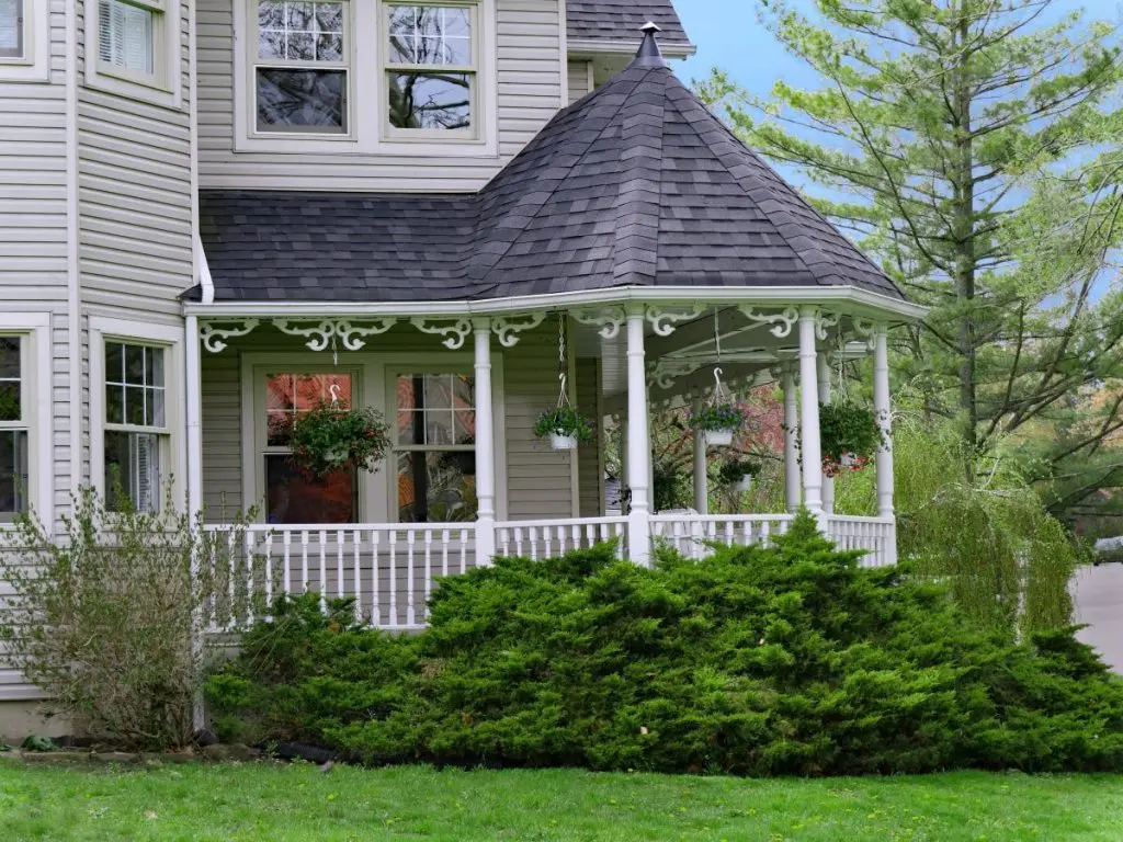 clapboard siding house with wrap around porch with cone shaped roof