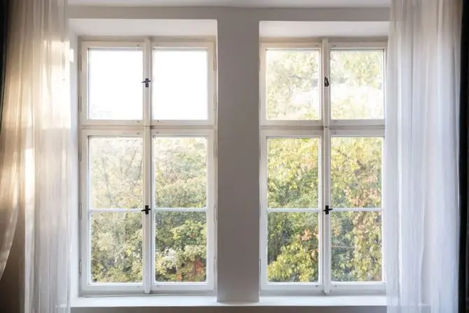large white windows with sheer curtains showing fall foliage outside