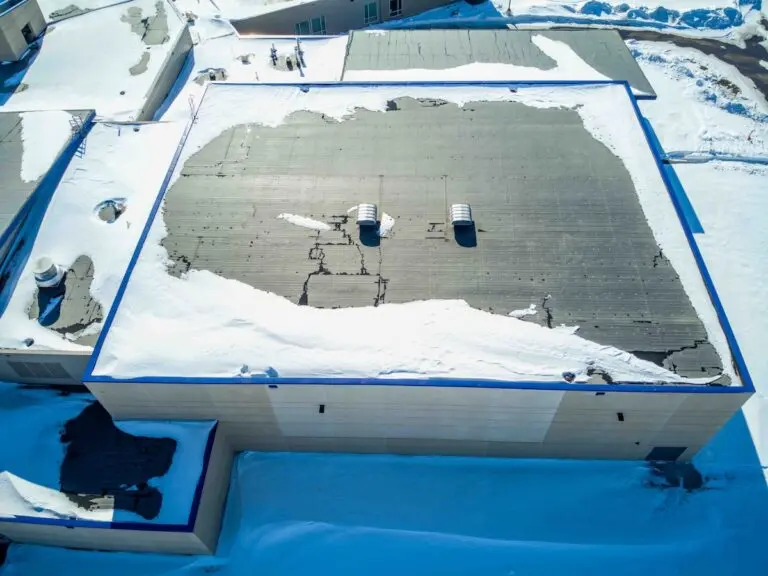 Elevated overhead drone view of a flat roofed building with snow load and ventilation units.