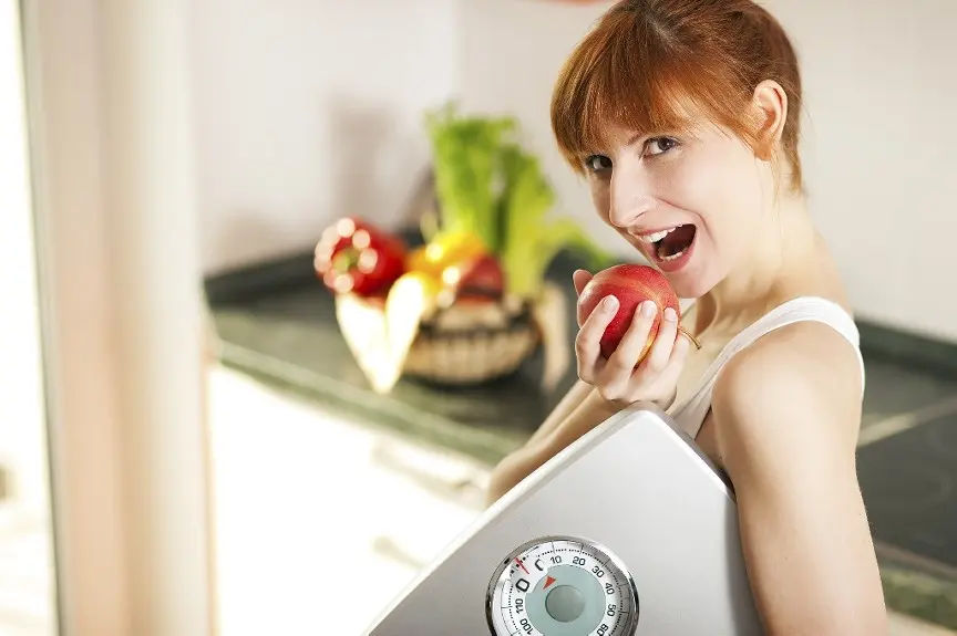 Lady smiling with a scale in her hand